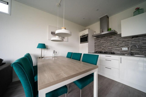 Cocina y comedor modernos en Pavilion Waterfront, EuroParcs Veluwemeer, Países Bajos, con sillas verdes.