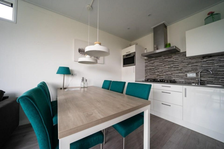Modern kitchen and dining area at Pavilion Waterfront, EuroParcs Veluwemeer, Netherlands with green chairs.