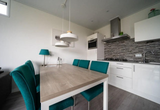 Cocina y comedor modernos en Pavilion Waterfront, EuroParcs Veluwemeer, Países Bajos, con sillas verdes.