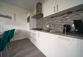 Cocina moderna en el lodge Pavilion Waterfront de EuroParcs Veluwemeer, Países Bajos, con gabinetes blancos.