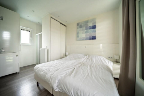 Dormitorio moderno en Pavilion Waterfront, EuroParcs Veluwemeer, Países Bajos, con cama doble y decoración clara.