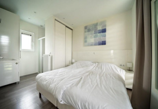 Dormitorio moderno en Pavilion Waterfront, EuroParcs Veluwemeer, Países Bajos, con cama doble y decoración clara.