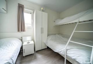 Chambre moderne à la Pavilion Waterfront au EuroParcs Veluwemeer, Pays-Bas, avec lits superposés blancs.