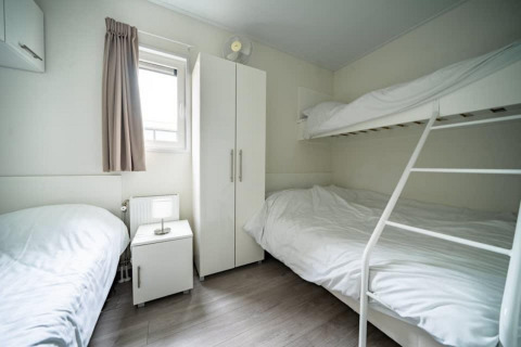 Chambre moderne à la Pavilion Waterfront au EuroParcs Veluwemeer, Pays-Bas, avec lits superposés blancs.