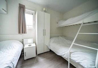 Habitación moderna en Pavilion Waterfront Lodge en EuroParcs Veluwemeer, Países Bajos, con literas blancas.