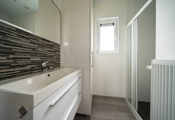 Baño moderno en Pavilion Waterfront, EuroParcs Veluwemeer, con ducha acristalada, ventana y lavabo.