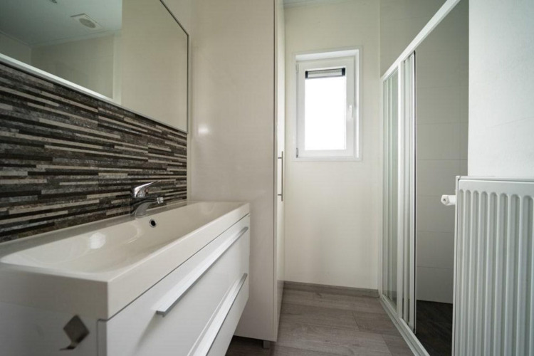 Modern bathroom at Pavilion Waterfront, EuroParcs Veluwemeer, featuring a shower, window and sink.