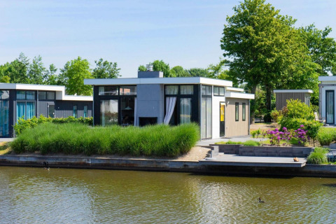 Moderne waterkant lodge bij EuroParcs Veluwemeer, Nederland, omgeven door groen en rustig water.