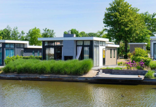 Moderne waterkant lodge bij EuroParcs Veluwemeer, Nederland, omgeven door groen en rustig water.