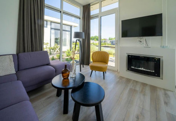 Moderne leefruimte in Pavilion Waterfront lodge bij EuroParcs Veluwemeer met grote ramen en stijlvolle inrichting.