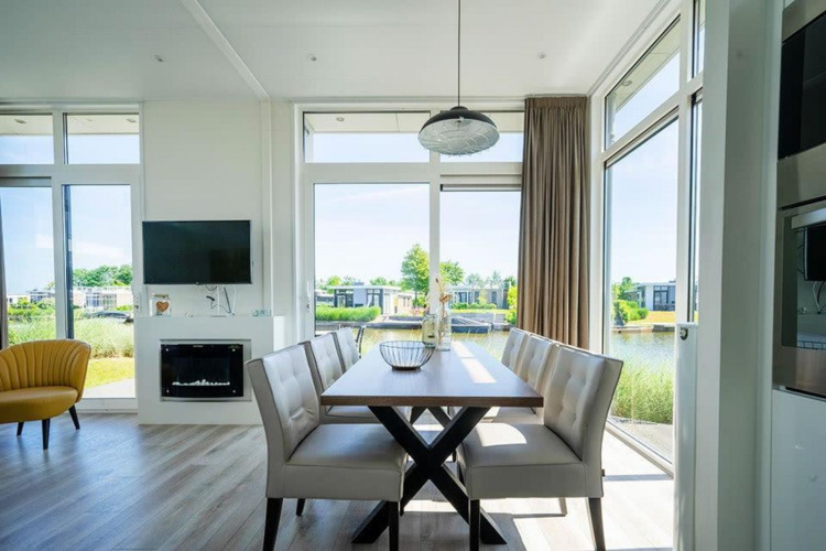 Luminoso comedor en el lodge Pavilion Waterfront de EuroParcs Veluwemeer, con grandes ventanas y vistas al lago.