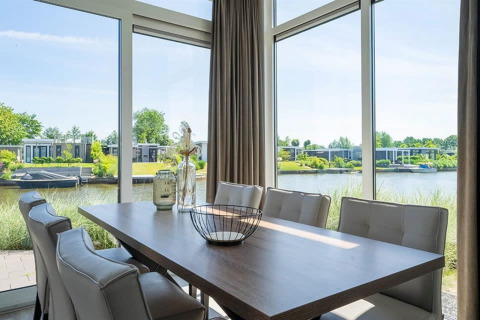 Eethoek met grote ramen, uitzicht op het water en moderne lodges in Pavilion Waterfront bij EuroParcs Veluwemeer.