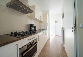 Cuisine moderne et étroite au Pavilion Waterfront d’EuroParcs Veluwemeer, Pays-Bas, avec cuisinière et cafetière.