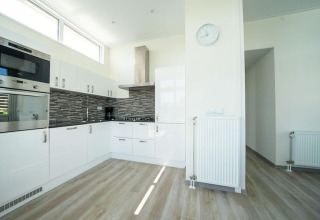 Cucina moderna al lodge Pavilion Waterfront di EuroParcs Veluwemeer, Paesi Bassi, con mobili bianchi.