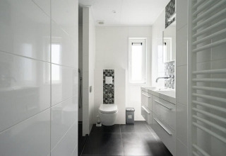 Modernes weißes Badezimmer im Pavilion Waterfront, EuroParcs Veluwemeer, mit dunklem Boden und Fenster.