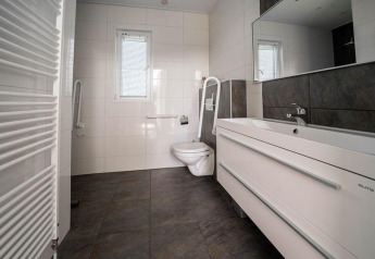 Moderne badeværelse med vægmonteret toilet, håndvaske og store fliser på lodgen Pavilion Waterfront.