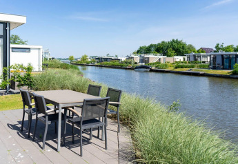 Mesa de comedor exterior en la terraza del Pavilion Waterfront con vistas al canal en EuroParcs Veluwemeer, Países Bajos.