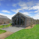 Udsigt til Solo Retreat lodge med træbeklædning, terrasse, græsplæne og klar blå himmel.
