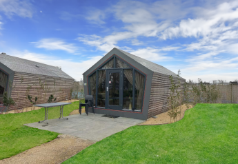 Vue extérieure du lodge Solo Retreat avec bardage bois, terrasse et jardin sous un ciel bleu.