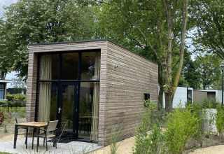 Pequeña casa moderna de madera con grandes ventanales en EuroParcs Veluwemeer, Países Bajos, rodeada de naturaleza.