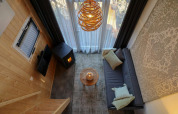 Salon confortable dans un Tiny House à EuroParcs Veluwemeer avec canapé, poêle et grandes fenêtres lumineuses.