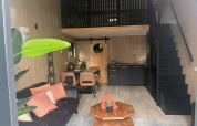 Moderne glampingverblijf met zithoek, kitchenette, eettafel en slaapvide in een gezellige stijl.