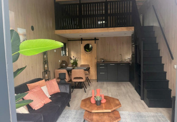Alloggio glamping moderno con zona giorno accogliente, angolo cottura, soppalco e tavolo da pranzo.