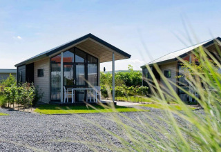 Modern tiny house with glass facade and small terrace at EuroParcs Veluwemeer in the Netherlands, sunny day.