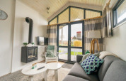Salon confortable dans un Tiny House à EuroParcs Veluwemeer, Pays-Bas, avec cheminée et grandes fenêtres.