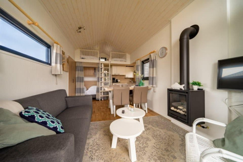 Cozy living area inside a tiny house at EuroParcs Veluwemeer, Netherlands, featuring modern decor and stove.