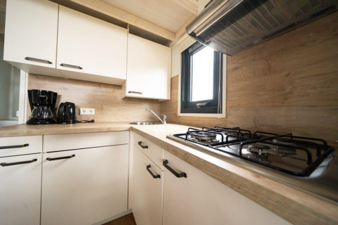 Cocina compacta en una tiny house en EuroParcs Veluwemeer, Países Bajos, con estufa de gas y electrodomésticos modernos.