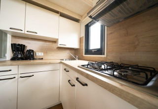 Cocina compacta en una tiny house en EuroParcs Veluwemeer, Países Bajos, con estufa de gas y electrodomésticos modernos.