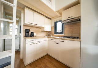 Modern compact kitchen in a tiny house at EuroParcs Veluwemeer in the Netherlands, with wood accents.
