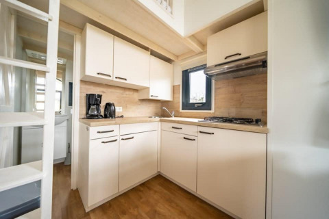 Cucina moderna e compatta in una tiny house a EuroParcs Veluwemeer, Paesi Bassi, con rifiniture in legno.