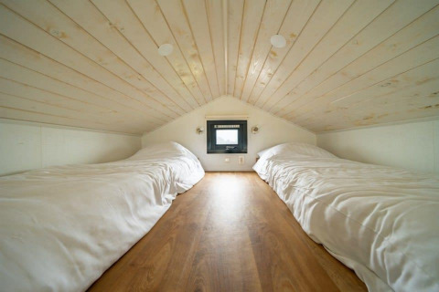 Cozy loft bedroom with two single beds and wooden ceiling in Tiny House at EuroParcs Veluwemeer, Netherlands.
