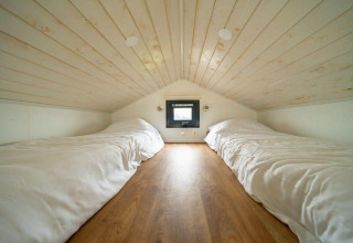 Cozy loft bedroom with two single beds and wooden ceiling in Tiny House at EuroParcs Veluwemeer, Netherlands.