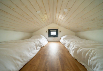 Chambre en mezzanine avec deux lits simples dans une tiny house à EuroParcs Veluwemeer, Pays-Bas.