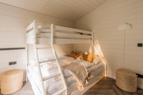 Bright bedroom with white bunk bed, cozy decor, and sunlight at Lakehouse + hottub, Wilsumer Berge, Germany.