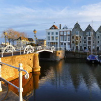 Brücke und typische Häuser am Wasser bei Sonnenaufgang in Westkapelle, Zeeland, Niederlande.