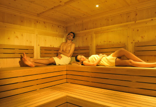 Zwei Personen entspannen sich in einer Holzsauna im Camping Seeblick Toni, einem Ferienpark in Tirol, Österreich.