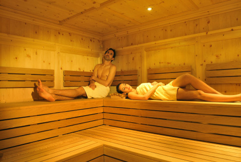 Due persone si rilassano in una sauna di legno presso Camping Seeblick Toni, un villaggio turistico in Tirolo, Austria.