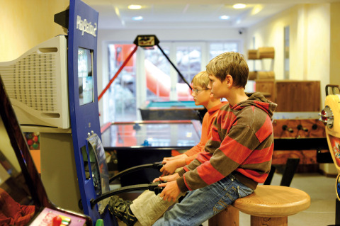 Dos niños juegan a un videojuego de arcade en la sala de juegos de Camping Seeblick Toni, Austria.