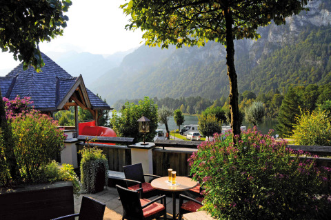 Vista desde la terraza en Camping Seeblick Toni, Tirol, con montañas, lago y vegetación exuberante al fondo.