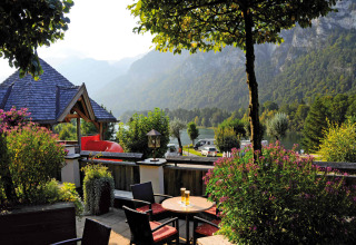 Zicht op het terras bij Camping Seeblick Toni in Tirol, met bergen, meer en weelderige natuur op de achtergrond.