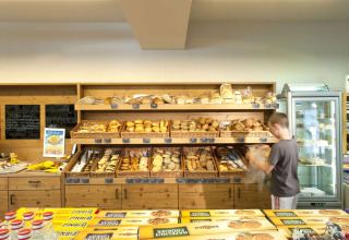 Ein Junge wählt frisches Brot in der Bäckerei im Camping Seeblick Toni, Ferienpark in Tirol, Österreich.