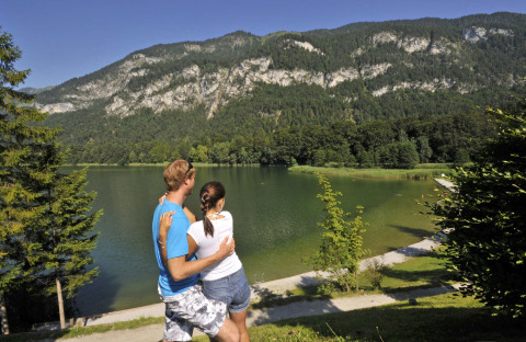 Una pareja disfruta la vista de un lago y montañas en Camping Seeblick Toni, un parque vacacional en Tirol, Austria.