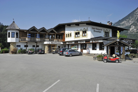 Camping Seeblick Toni en Tirol, Austria, con restaurante, coches aparcados y un paisaje montañoso de fondo.