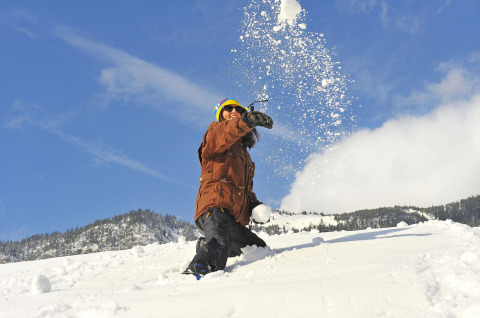 Persona che lancia una palla di neve al Camping Seeblick Toni in Tirolo, Austria, circondata da montagne innevate.