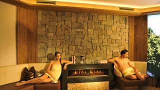 Zona wellness relajante con dos huéspedes junto a la chimenea en Camping Seeblick Toni, Tirol, Austria.