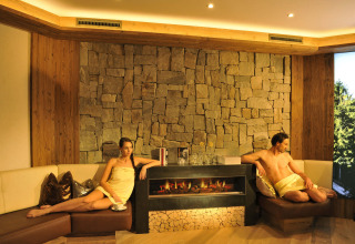 Zona wellness relajante con dos huéspedes junto a la chimenea en Camping Seeblick Toni, Tirol, Austria.